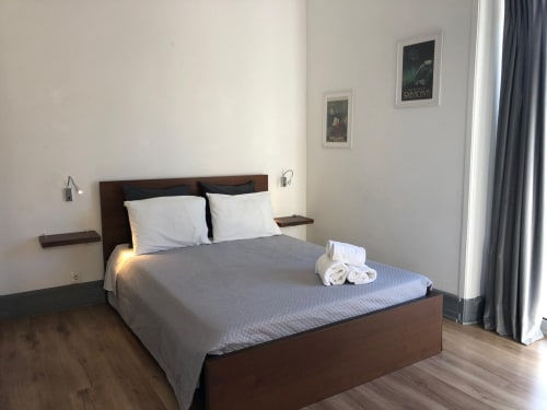 Quarto duplo de luxo na Pousada Infante Dom Henrique em Coimbra com cama de madeira, almofadas brancas, roupa de cama cinzenta e vista da cidade