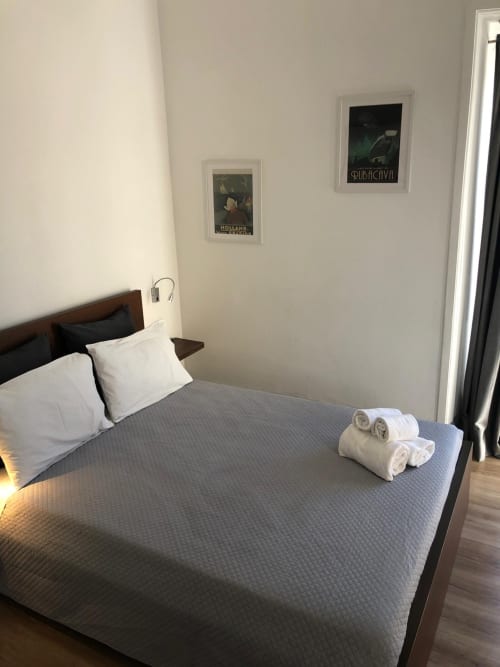 Quarto moderno da Guest House Infante Dom Henrique em Coimbra com cama queen, almofadas brancas, toalhas dobradas e estilo vintage