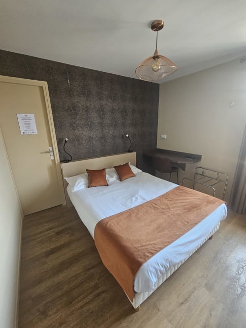 Chambre double moderne de l'Hôtel La Route d'Argent à Bozouls, avec literie blanche et accents cuivrés
