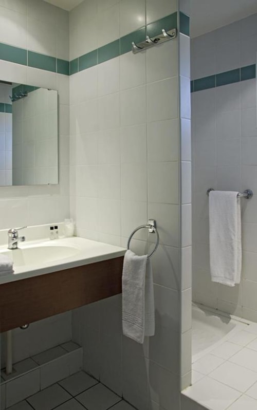 Salle de bain moderne de la Chambre Triple Confort à l'Hôtel La Route d'Argent, Bozouls avec lavabo, douche et porte-serviettes