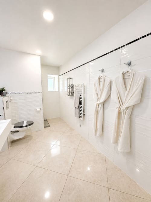 Salle de bains spacieuse et moderne à la Chambre La Milande du gîte La Biche Au Bois, Moncléra, avec carrelage blanc et peignoirs crème