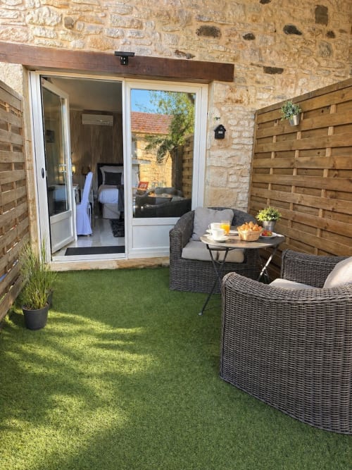 Patio jardin cosy de La Biche Au Bois avec sièges en osier, table bistrot et accès direct à la Chambre La Milande