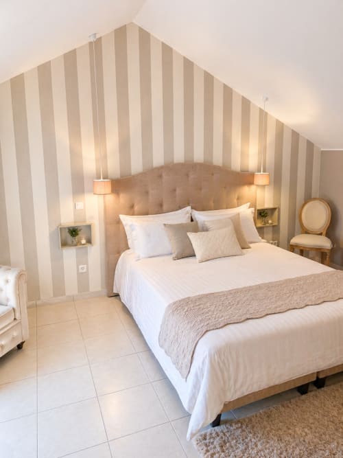 Suite élégante à La Biche Au Bois avec papier peint rayé, tête de lit beige et éclairage contemporain