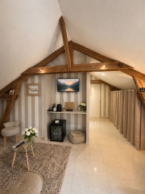 Suite de luxe avec poutres en bois apparentes, papier peint rayé, cheminée et équipements modernes à La Biche Au Bois B&B
