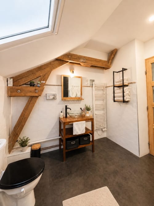 Salle de bains rustique avec poutres apparentes, meuble en bois et équipements modernes au gîte La Biche Au Bois à Moncléra, France