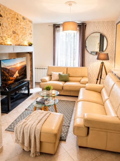 Élégant salon du Gîte Le Tranquille avec canapés en cuir beige, cheminée et décoration moderne à Moncléra