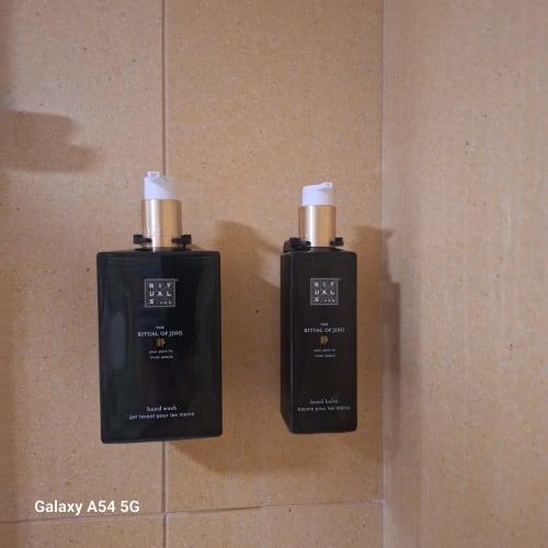 Two black Rituals hand wash and balm bottles with gold dispensers hanging in hotel bathroom at AL Penaferrim Sintra