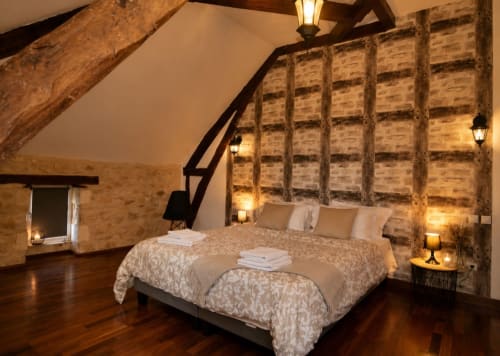 Chambre rustique à la Biche Au Bois avec poutres apparentes, murs de brique et éclairage d'ambiance