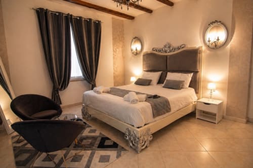 Chambre luxueuse du gîte La Biche Au Bois à Moncléra avec lit queen-size, fauteuils noirs, miroirs ornementés et éclairage chaleureux