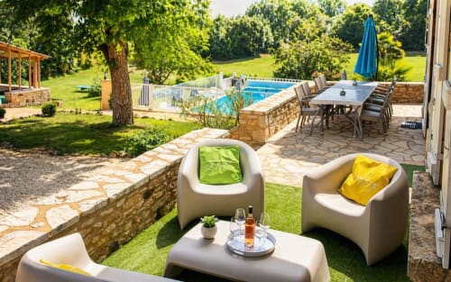 Espace de détente au bord de la piscine du gîte La Biche Au Bois avec mobilier moderne, pelouse verte et parasols bleus surplombant la piscine