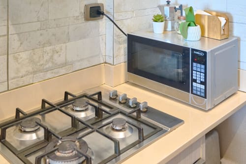 Modern kitchen in luxury apartment with gas stove, microwave, and tile backsplash in Santo Domingo