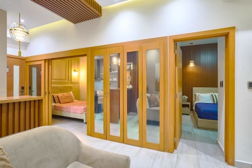 Luxury apartment in Santo Domingo with golden wood doors, modern furnishings, and multiple bedrooms visible through glass