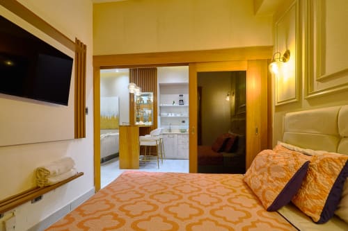 Luxurious apartment bedroom in Downtown Santo Domingo with modern furnishings, orange bedding, flat-screen TV, and