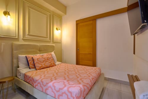 Luxurious studio apartment in downtown Santo Domingo with queen bed, cream headboard, orange geometric bedding, and modern