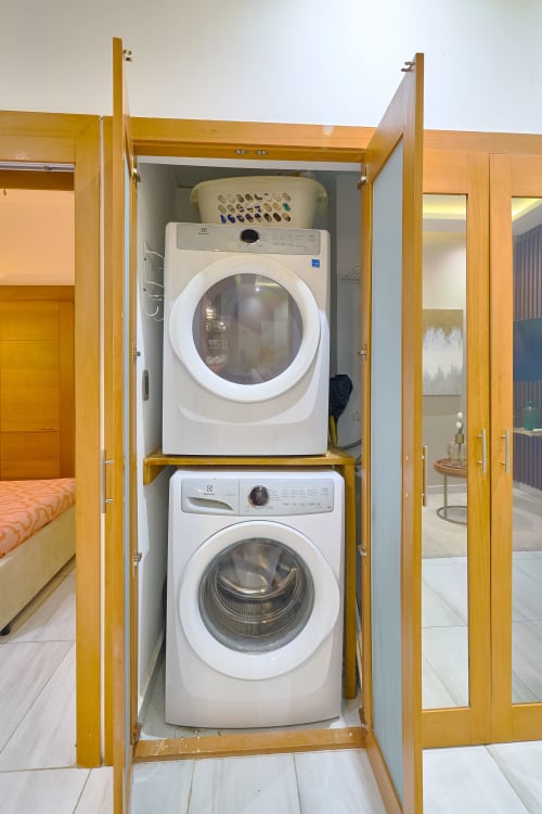 Stacked washer and dryer in wooden cabinet closet at luxury downtown Santo Domingo apartment