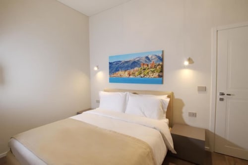 Camera da letto moderna nell'appartamento Le Due Piazze con vista panoramica urbana, biancheria bianca e illuminazione contemporanea