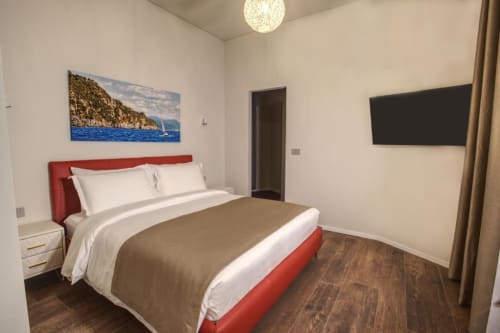 Camera moderna del Le Due Piazze BnB a Genova con testata rossa, TV a schermo piatto e quadri di barche a vela