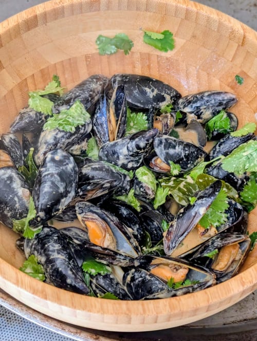 Mejillones al vapor frescos con guarnición de cilantro en cuenco de madera en el hotel Cala Pipa, Tarragona