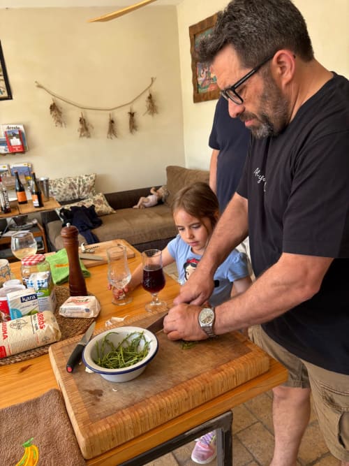 Padre e hija cocinando juntos en la cocina de Poble Nou del Delta, preparando judías verdes en el hotel Cala Pipa