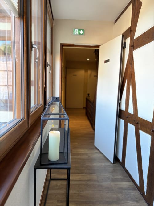 Corridor moderne de l'Hôtel de l'Ange avec lanterne à bougies, fenêtres en bois et panneaux de sortie de secours