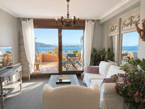 Luminosa sala de estar del apartamento en Baiona con vistas al mar, muebles blancos, flores y acceso a terraza