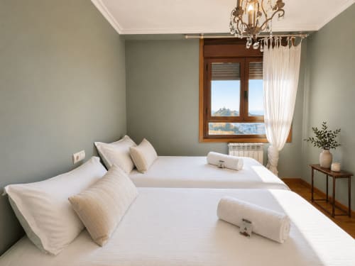 Dormitorio moderno y luminoso en Baiona con camas gemelas, vistas al mar, marcos de madera, ropa de cama blanca impecable y decoración costera