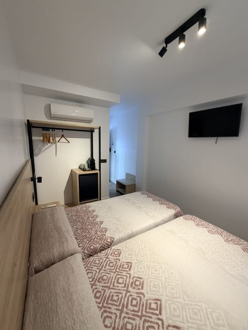 Moderno dormitorio doble en Hostal Juan Carlos de Carboneras con camas gemelas, TV, aire acondicionado y decoración minimalista