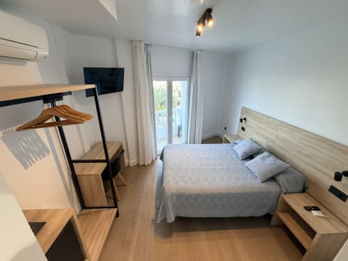Moderno dormitorio doble en Hostal Juan Carlos en Carboneras con cama, escritorio, TV y acceso a balcón
