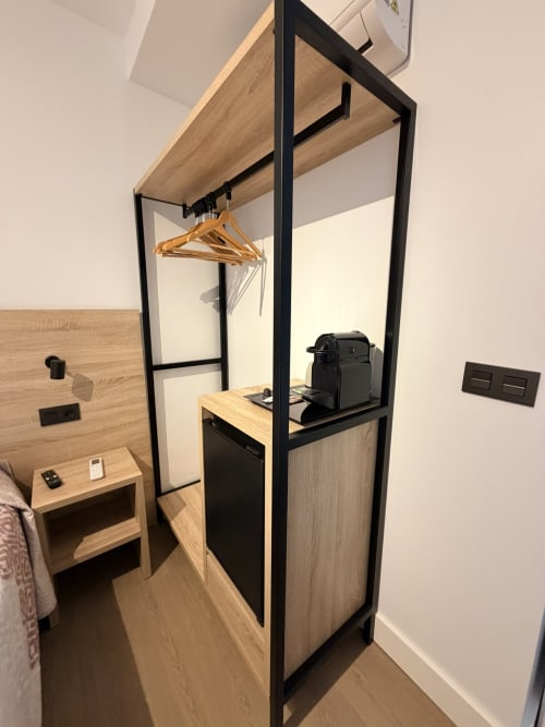 Armario moderno con marco negro, superficies de madera y ropa colgada en Hostal Juan Carlos, Carboneras