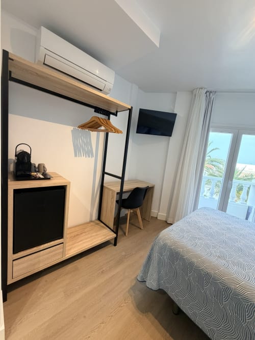 Moderno dormitorio doble en el Hostal Juan Carlos de Carboneras con muebles de madera, TV, aire acondicionado, escritorio y vistas al mar