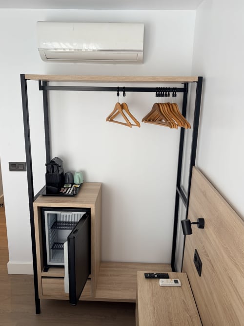Armario moderno y minibar en la habitación doble del Hostal Juan Carlos, Carboneras, con perchas de madera y aire acondicionado