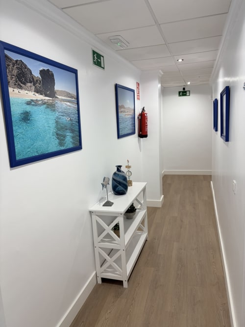 Pasillo moderno del Hostal Juan Carlos en Carboneras con obras de arte costera, consola blanca y decoración náutica