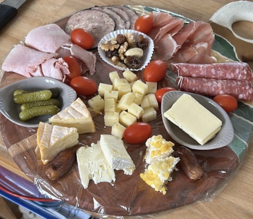Plateau de charcuterie à La Villa Plein Vent avec charcuteries, fromages, cornichons, tomates, noix et crackers.