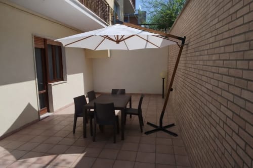 Terrazza esterna di Tales of Abruzzo Atessa con tavolo da pranzo, sedie nere e ombrellone cantilever