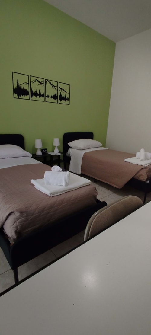 Camera doppia dell'hotel Tales of Abruzzo ad Atessa con parete verde lime, letti neri, biancheria bianca e quadri con paesaggi montani