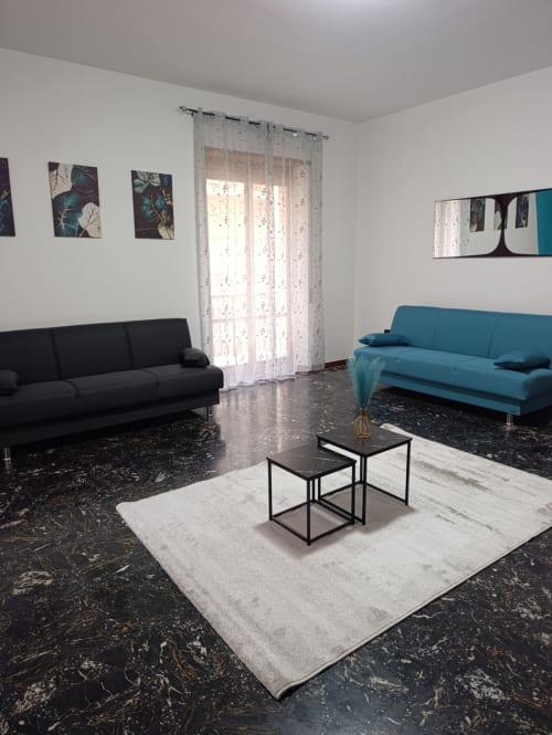 Elegante soggiorno con divani neri e turchesi, pavimenti in marmo e porte in vetro dell'appartamento Tales of Abruzzo ad Atessa