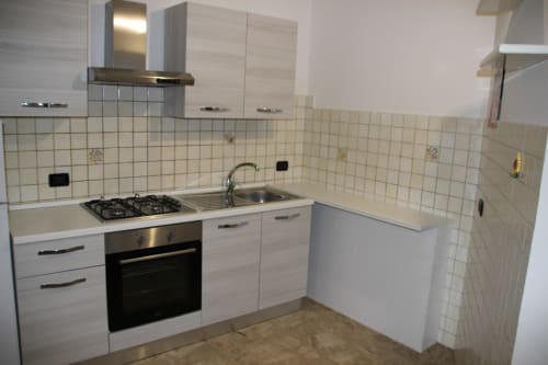 Cucina moderna nell'appartamento Due Orizzonti ad Atessa, Italia - dotata di fornello, lavello, armadi bianchi e rivestimento in piastrelle
