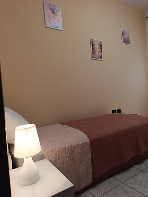 Camera con due letti, lampada da comodino bianca e opere d'arte incorniciate presso l'hotel Tales of Abruzzo ad Atessa, Italia