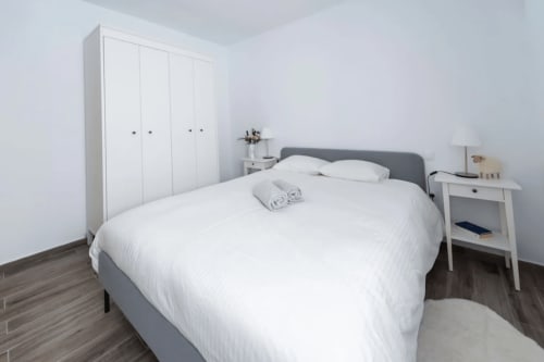 Dormitorio moderno en Smart Rent Fuerteventura con cama gris, armario blanco y decoración minimalista
