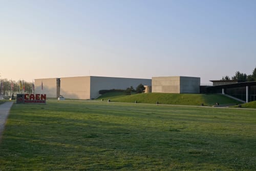 Modern architecture of Hotel De Lion Sur Mer with sloped green lawn and tan/grey building in Lion sur Mer, France