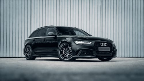 Monospace Audi RS6 Avant noir présenté devant un fond en tôle ondulée