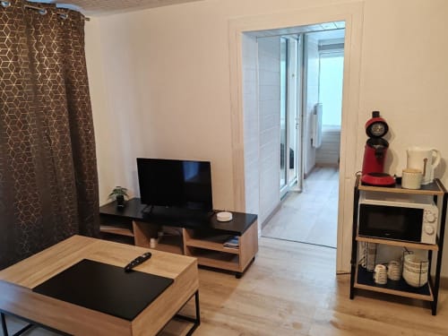 Espace de vie cottage moderne aux Gîtes De Petrocoriis avec téléviseur, mobilier bois et cuisine équipée