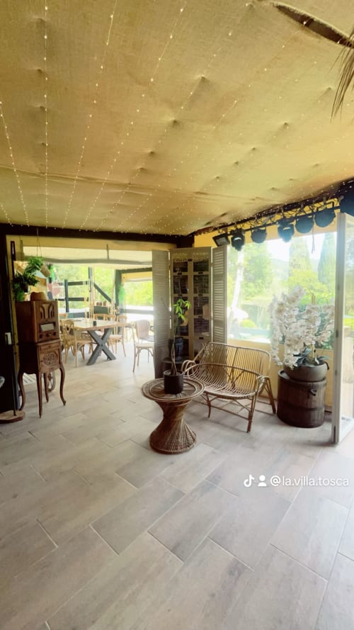 La véranda de la Villa Tosca avec guirlandes lumineuses, mobilier en rotin et vue sur le jardin à Callas