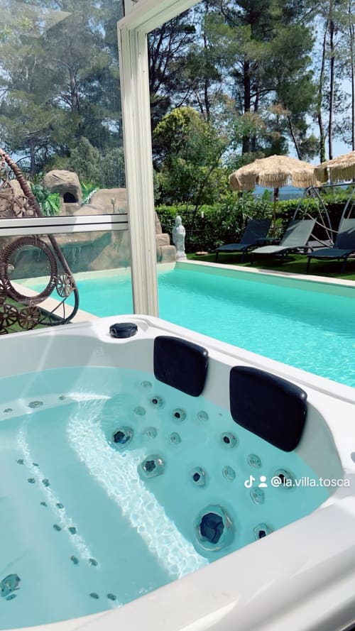 Magnifique bain à remous à La Villa Tosca à Callias avec vue sur la piscine turquoise et les jardins boisés
