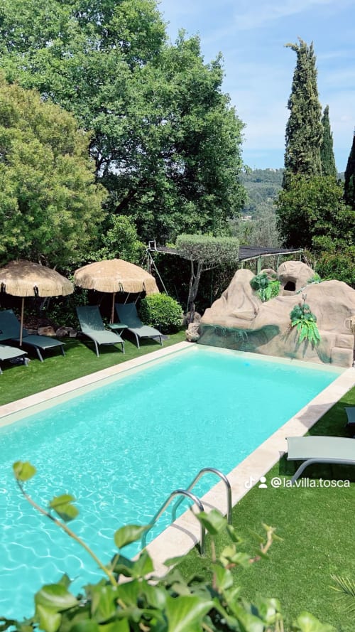 La piscine et la terrasse de la Villa Tosca avec chaises longues, parasols et éléments rocheux à Callas, France