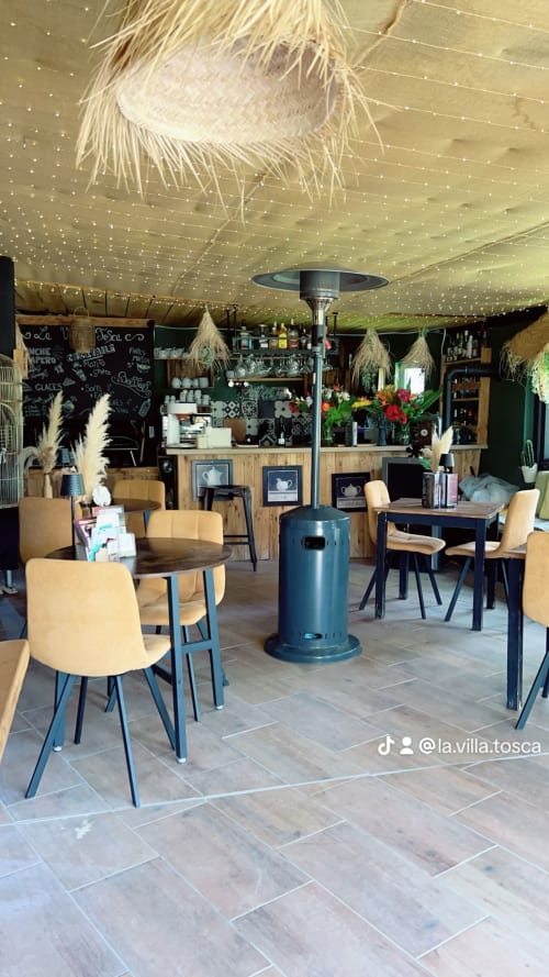 Le salon La Villa Tosca avec chauffage infrarouge, fauteuils beige, bar en bois et guirlandes lumineuses à Callas