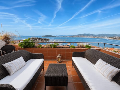 Terraza dúplex Lar de Mar en Baiona con muebles de mimbre, vistas al mar con barcos y pueblo costero