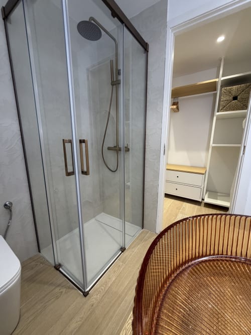 Modern bathroom at Villa Alegria with glass shower enclosure, rainfall showerhead, and walk-in closet in Cala d'Or
