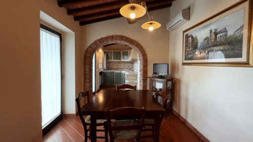 Zona pranzo dell'appartamento deluxe a Borgo di Erboli, Cavriglia con tavolo in legno, arco in mattoni e accesso alla cucina