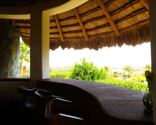 Terraza sombreada en El Origen Villas con vistas a los jardines tropicales y el océano en Puerto Escondido, México